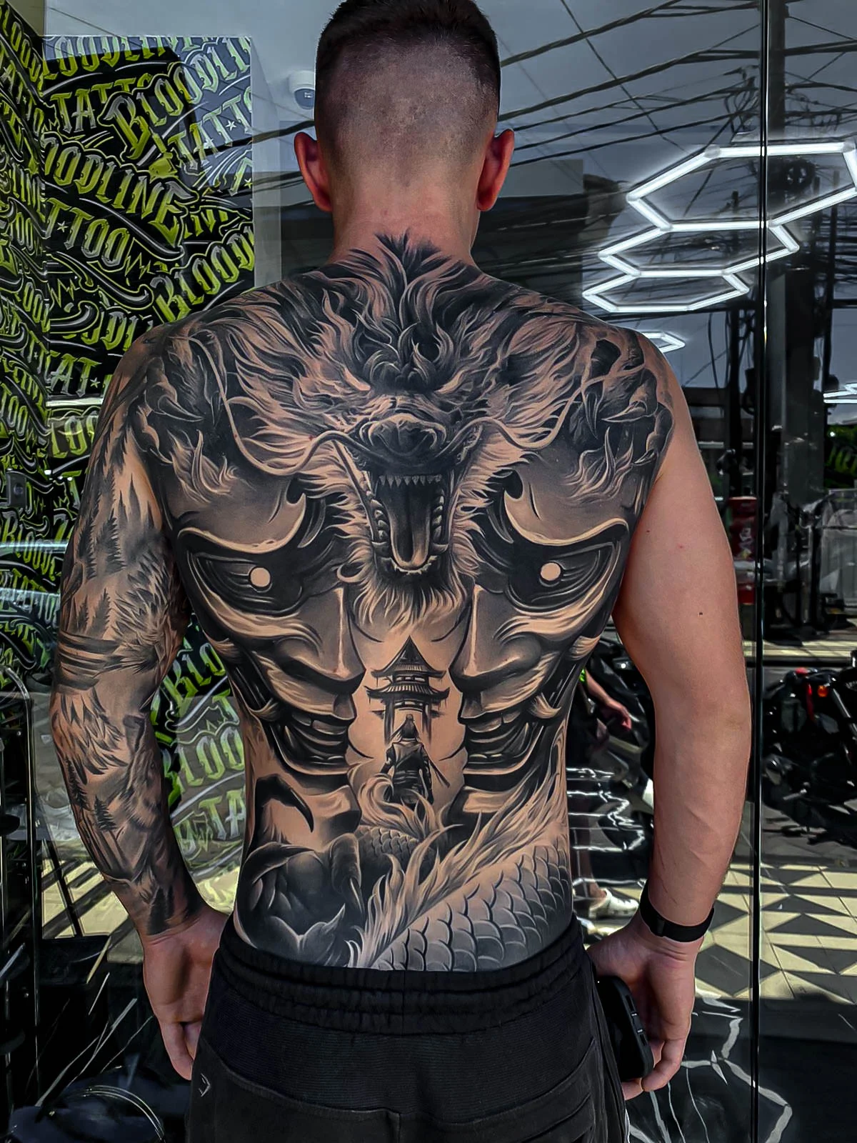 Healed full-back dragon piece with mirrored Hannya masks, pagoda depth, and soft black-and-grey transitions that keep strong line integrity at Bloodline Tattoo Bali.
