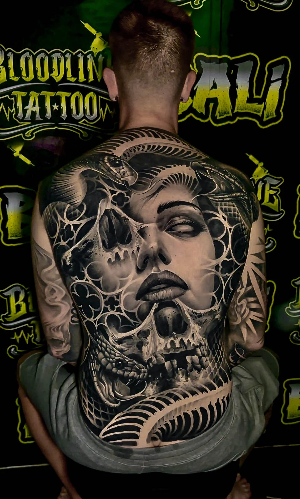 Healed full-back piece with a woman's face, skulls, and coiling snakes, showing smooth black-and-grey blending and strong healed contrast at Bloodline Tattoo Bali.