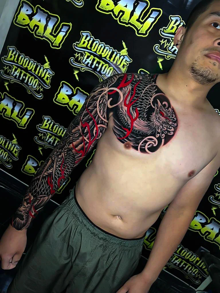 Black and grey Japanese chest-to-hand sleeve with a phoenix, tiger, and red wind bars at Bloodline Tattoo Bali.