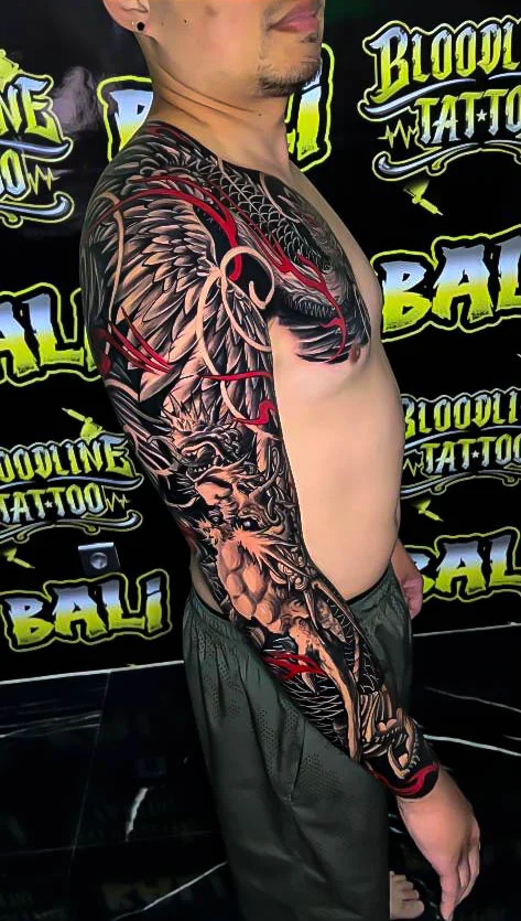 Black and grey Japanese chest and full sleeve with a phoenix, tiger, and red wind bars at Bloodline Tattoo Bali.