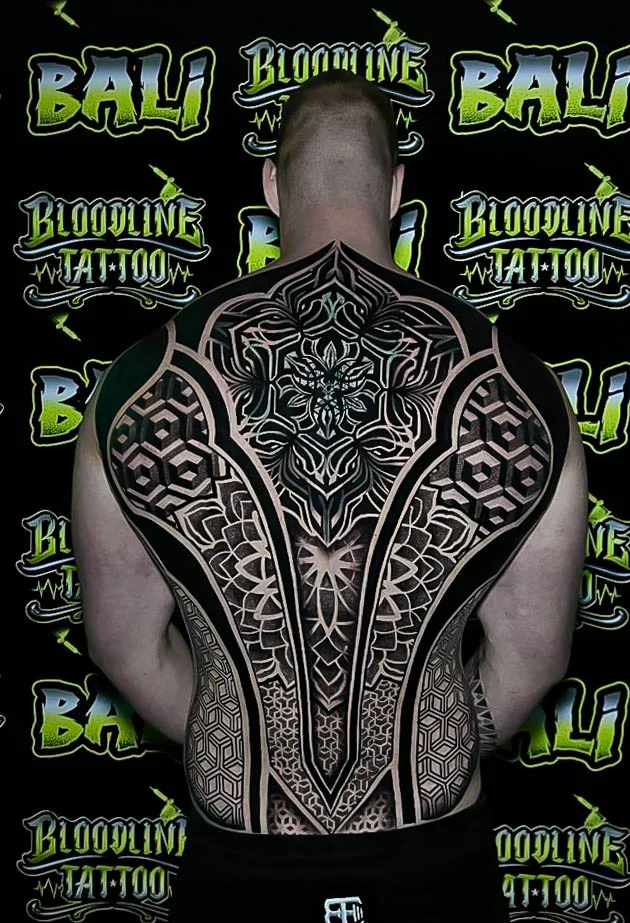 Full-back sacred geometry suit with cube tessellation, lotus-based symmetry, and layered blackwork panels running shoulder to waist at Bloodline Tattoo Bali.