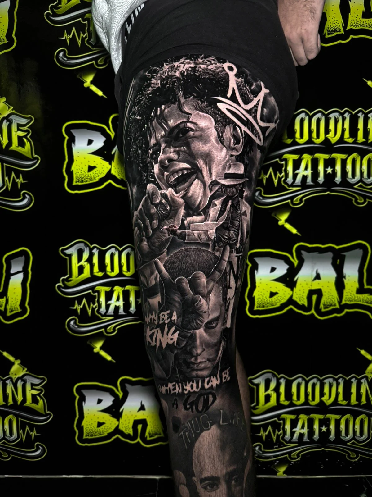 Black and grey portrait realism thigh tattoo featuring Michael Jackson, Eminem, Tupac, and bold rap-inspired lettering at Bloodline Tattoo Bali.
