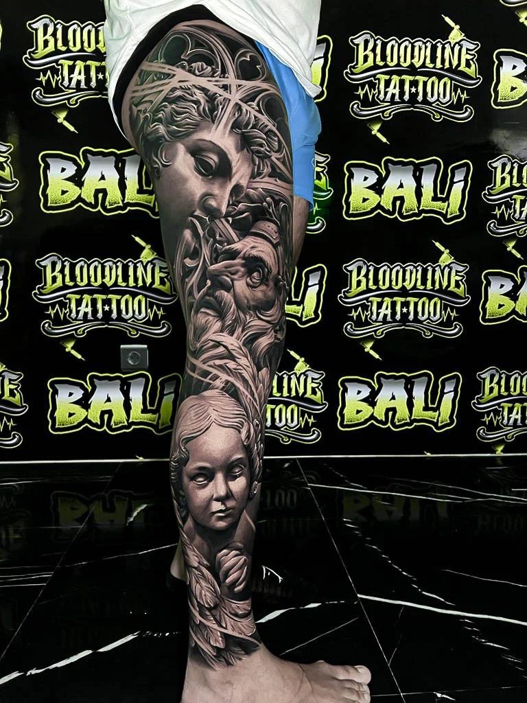 A black and grey realism arm sleeve with classical female portraits, sculptural facial features, and soft smoky transitions down the forearm, at Bloodline Tattoo Bali.